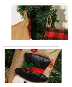 Macro detail of Christmas stocking with snowman embroidery and red plaid trim on a tree