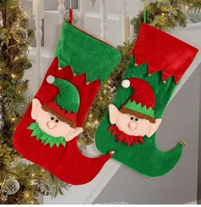 Detail of red and green Christmas elf stockings with bells hanging on fireplace garland