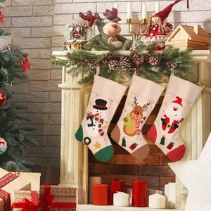 Drei große Weihnachtsstrümpfe mit Schneemann Rentier und Weihnachtsmann am Kamin hängend