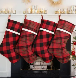 Set of four red and black buffalo plaid Christmas stockings hanging on a white fireplace