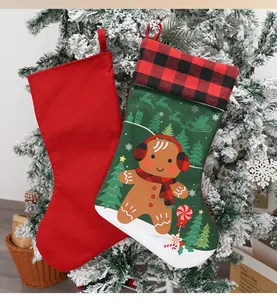 Close-up of Christmas stockings with gingerbread and reindeer patterns on snowy branches