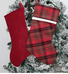 Detail of red velvet and plaid Christmas stockings hanging on snow-covered pine branches