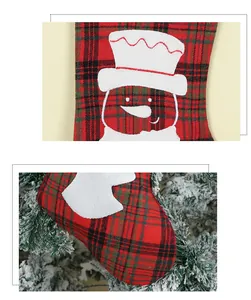 Close-up of red and green plaid Christmas stocking with snowman embroidery and branch detail