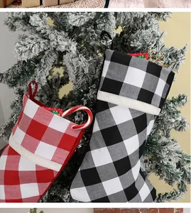 Detail of buffalo plaid Christmas stockings hanging on a snowy tree with candy canes