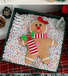 Detail view of plush gingerbread man ornament in a festive gift box for Christmas decor