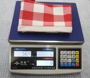 Detailed view of red and white plaid Christmas stocking being weighed at 56.4 grams