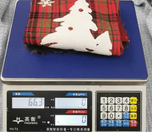 Close-up of a large plaid Christmas stocking weighing 66.3g on a precision digital scale
