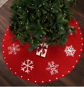 Detail van de rode gebreide kerstboomrok met witte sneeuwvlokpatronen en golvende randen
