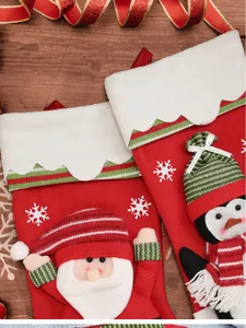 Detail view of red Christmas stockings featuring Santa and penguin plush ornaments