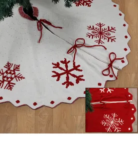 Detail van de gebreide kerstboomschort met sneeuwvlokken en rode strikjes