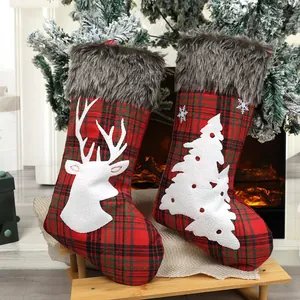 Plaid Christmas stockings with reindeer and tree appliques by the fireplace