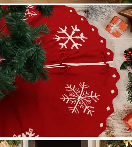 Detail van rood gebreide kerstboomrok met witte sneeuwvlokpatronen en rode strikbandjes