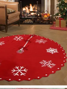 Detail van rode gebreide kerstboomschort met witte sneeuwvlokken en striksluitingen