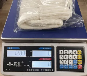 Primo piano di una calza di Natale in maglia bianca in confezione su bilancia da 120,4g