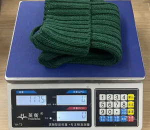 Dettaglio del berretto in maglia verde scuro su una bilancia che pesa 117,5g