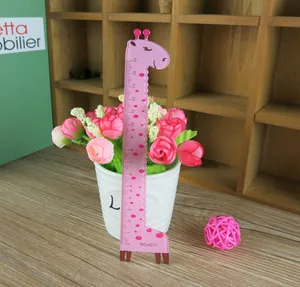 Close-up of pink giraffe-shaped plastic ruler with 15cm scale on dark wooden shelf