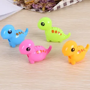 Cute cartoon dinosaur pencil sharpeners in four colors on a light wood background