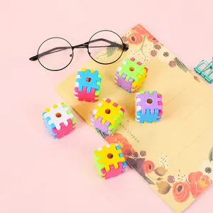 Macro shot of colorful Rubik cube pencil sharpener blocks arranged on a pink desktop