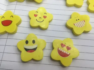 Dettaglio macro di gomme gialle a forma di stella con faccine sorridenti su carta