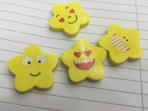 Set di quattro gomme gialle a forma di stella con diverse emoji su carta a righe