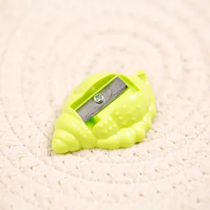 Cute green shell-shaped pencil sharpener for students on a textured background