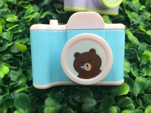 Macro shot of camera-shaped sharpener with cute bear design on artificial green leaves