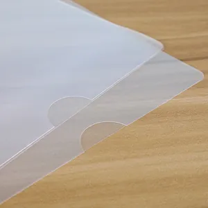 Detail of semi-transparent A4 folder with thumb notch on a light wood desk surface