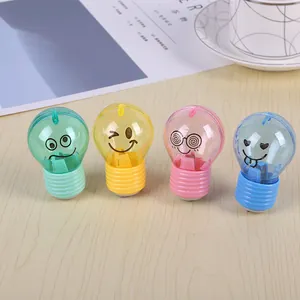 Detail view of light bulb shaped pencil sharpeners in four pastel colors on a wooden table