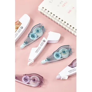 Détail des rubans correcteurs CR-2020 blancs et bleus sur un fond rose pastel