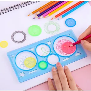 Mains d'enfant utilisant un kit de règle spirographe bleue pour dessins géométriques