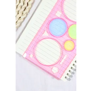 Règle de dessin Spirographe rose avec engrenages colorés sur un cahier pour la création
