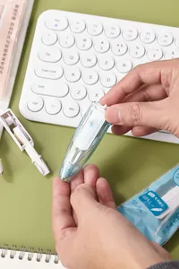 Détail du ruban correcteur rétractable et de sa recharge sur un bureau avec clavier
