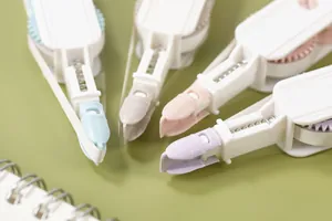 Vue détaillée de quatre rubans correcteurs rétractables colorés sur une surface verte épurée