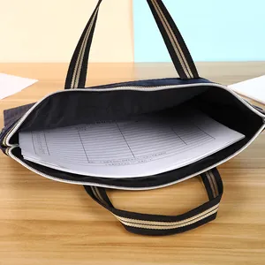 Waterproof navy oxford file bag with striped handles holding A4 documents on wooden desk