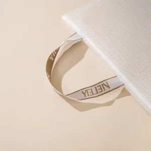 Close-up of translucent white mesh A4 file bag with beige woven reinforced handles
