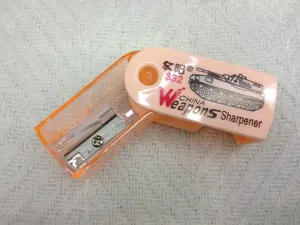 Detailed view of an orange mini pencil sharpener with rotating tank design and steel blade