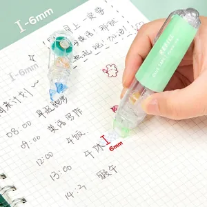 Detalle de rodillo de pegamento de 6mm verde menta aplicando cinta en un cuaderno