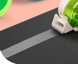 Detailopname van groene lijmroller die gladde witte plakband op zwart papier aanbrengt