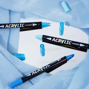 Detailed view of dual-tip blue acrylic markers reflecting on a mirror surface with fabric