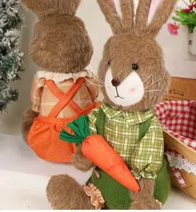Detail of Easter bunny figurines in plaid outfits holding a carrot in garden setting
