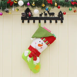 Chaussette de Noël verte avec bonhomme de neige et écharpe rouge sur mur en bois