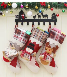 Détail de trois chaussettes de Noël 3D suspendues avec des décorations de branches vertes