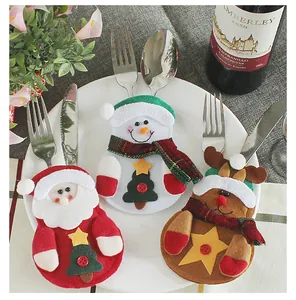 Detail view of Santa and snowman cutlery holders placed on a ceramic plate with silverware