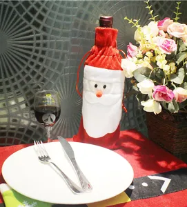 Dettaglio del copribottiglia di Babbo Natale in peluche rosso su tavola natalizia