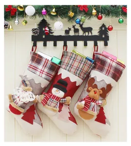 Trois chaussettes de Noël avec Père Noël, bonhomme de neige et renne sur mur en bois