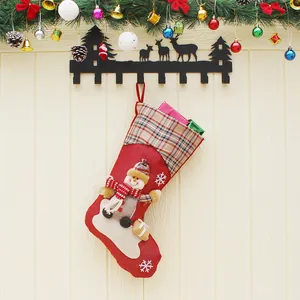 Large red Christmas stocking with snowman decor and plaid cuff hanging on a festive wreath