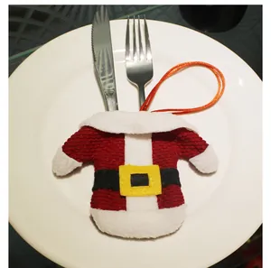 Close-up of Santa suit cutlery holder on white plate with metal fork and knife