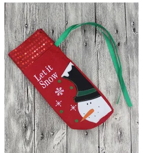 Detail of red Christmas gift bag with 'Let it Snow' snowman applique on wooden background