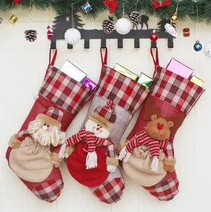 Three Christmas stockings with Santa, Snowman, and Reindeer 3D plush on ivory wood