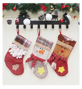 Three Christmas stockings with Santa, snowman and reindeer on a rustic wall